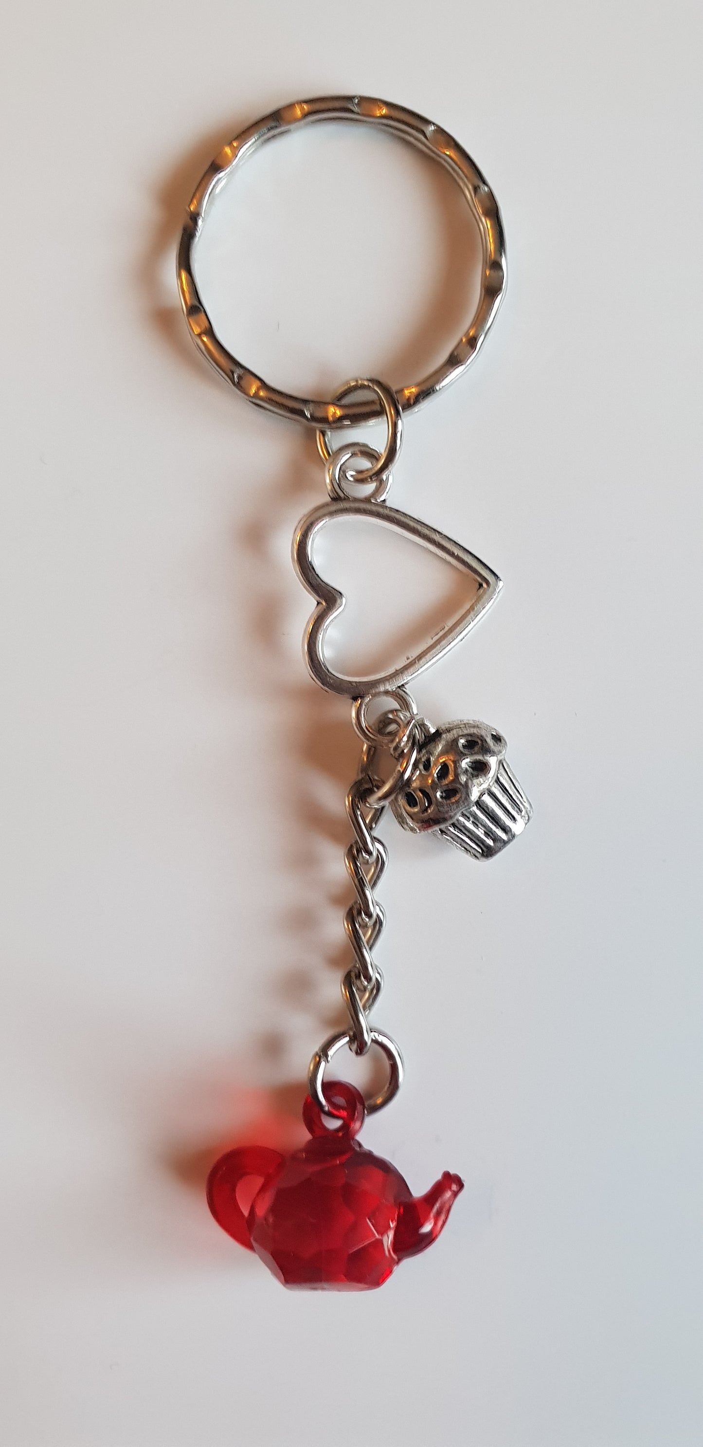 Love tea and cake keyring. Handmade using a tibetan silver heart charm with an alloy cupcake charm and an acrylic teapot charm, hanging from a keyring loop.
