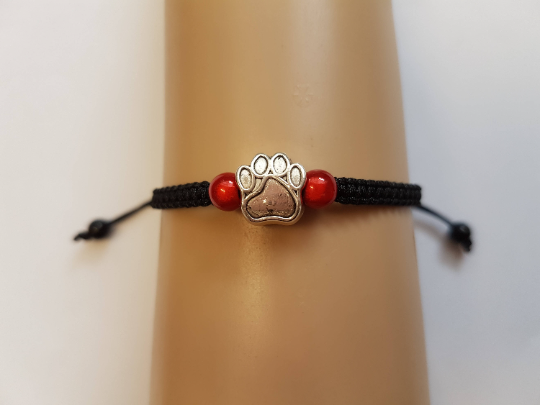 Paw print bracelet on black cord, with red beads.