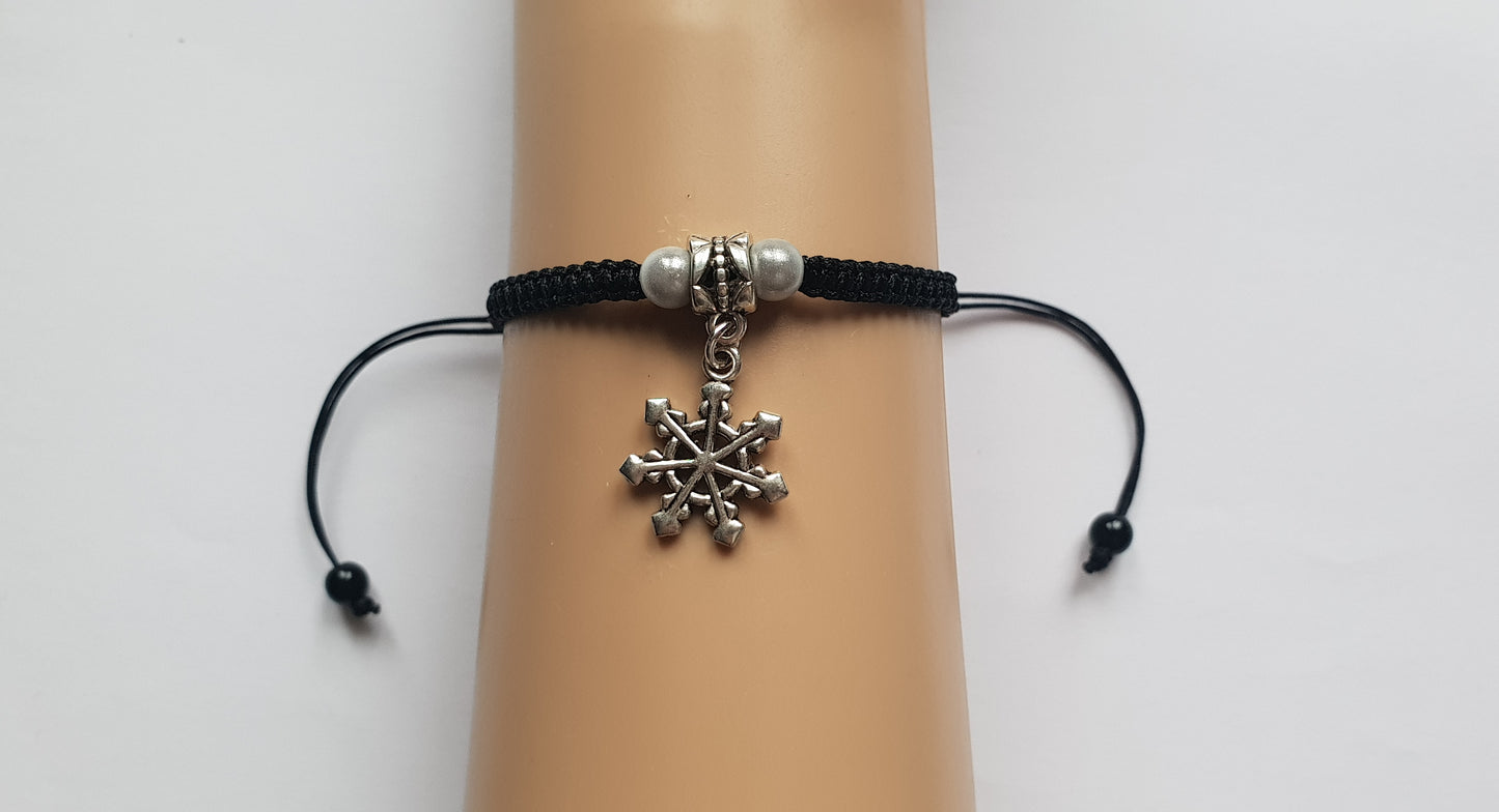 Snowflake charm bracelet.  This is a handmade adjustable black cord bracelet with a snowflake charm, with white beads either side.